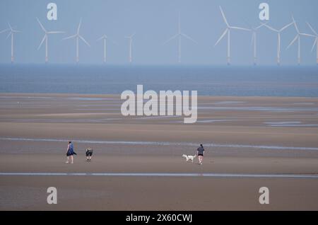 Persone che camminano con cani sulla spiaggia di New Brighton a Wirral, Merseyside. Data foto: Domenica 12 maggio 2024. Foto Stock