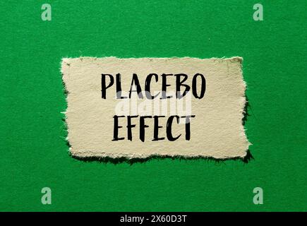 Parole con effetto placebo scritte su carta strappata con sfondo verde. Simbolo concettuale dell'effetto placebo. Copia spazio. Foto Stock