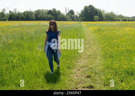 Eton, Windsor, Berkshire, Regno Unito. 12 maggio 2024. Una donna cammina attraverso un campo di tazze in una bella giornata di sole a Eton, Windsor, Berkshire. Si prevede che le temperature raggiungano di nuovo i 27 gradi oggi, tuttavia i temporali sono previsti più tardi. Crediti: Maureen McLean/Alamy Live News Foto Stock