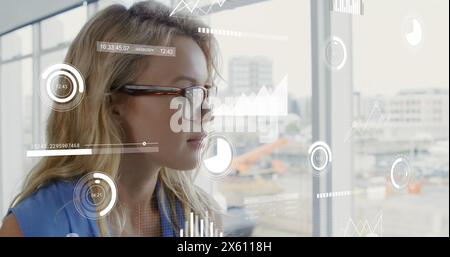 Immagine di grafici, numeri che cambiano, cerchi e barre di carico, donna caucasica premurosa Foto Stock