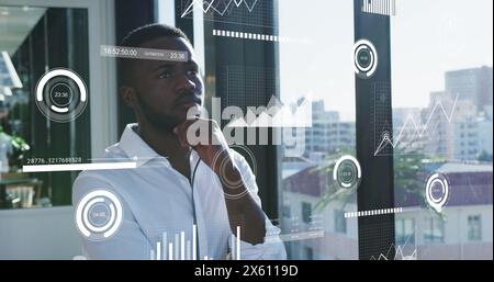 Immagine di grafici, numeri che cambiano, cerchi e barre di carico, un uomo afroamericano premuroso Foto Stock