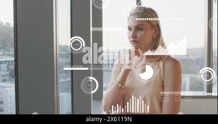 Immagine di grafici, cerchi di carico, barre, donna caucasica premurosa che guarda attraverso una finestra di vetro Foto Stock