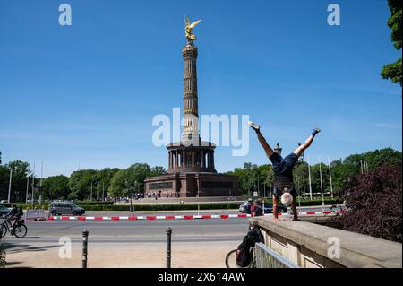 09.05.2024, Berlino, Deutschland, Europa - Ein Mann macht an einem sonnigen Tag auf einer niedrigen Mauer vor der Siegessaeule am Grossen Stern in Tiergarten einen Handstand. *** 09 05 2024, Berlino, Germania, Europa Un uomo fa un palco su una parete bassa di fronte alla colonna della Vittoria al Großer Stern di Tiergarten in una giornata di sole Foto Stock