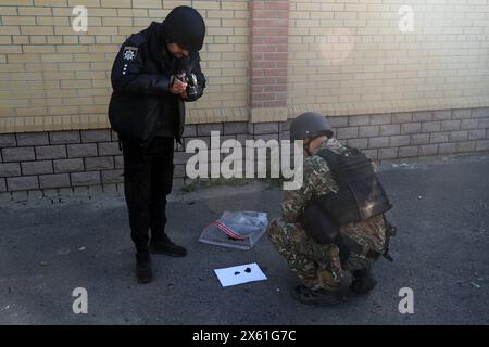 Non esclusiva: KHARKIV, UCRAINA - 10 MAGGIO 2024 - Un militare e un agente di polizia raccolgono prove dopo un attacco missilistico russo, Kharkiv, nord-est Foto Stock