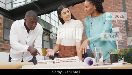 Immagine di numeri, icone nelle barre di notifica, colleghi diversi che discutono del progetto in ufficio Foto Stock