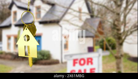 Immagine del portachiavi e della chiave della casa d'oro, appesi di fronte alla casa sfocata con un cartello per la vendita Foto Stock