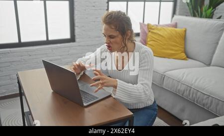 Frustrata giovane donna caucasica che usa un notebook in un moderno salotto al chiuso Foto Stock