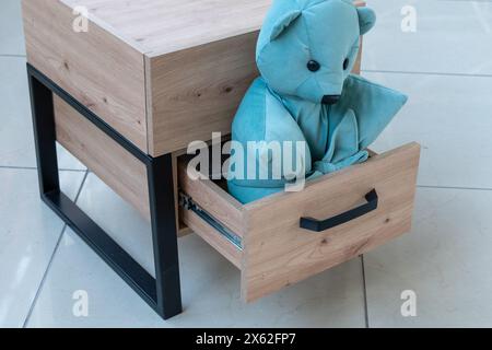 Mobili per armadi. Peluche blu in un cassetto aperto del comodino in legno Foto Stock