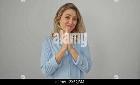 Ritratto di una giovane donna bionda caucasica con le mani unite, su uno sfondo bianco. Foto Stock