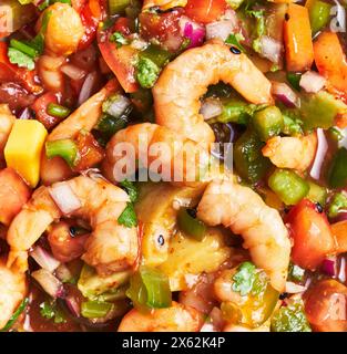 Primo piano di una colorata ceviche di gamberi con pomodori freschi, coriandolo, cipolle e mango. Foto Stock