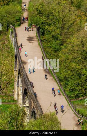 Persone che si godono il sole primaverile camminando e pedalando lungo il Monsal Trail sul viadotto di lapide a Monsal Head, dove attraversa il fiume Wye Foto Stock