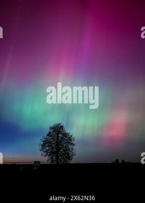 Una bella aurora verde e rossa che danzano sulle colline Foto Stock