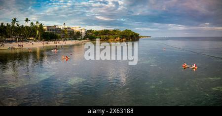 Invitante scena costiera di Alona Beach nel tardo pomeriggio, evidenziando le acque tranquille e le attività piacevoli degli amanti della spiaggia. Un'immagine Foto Stock