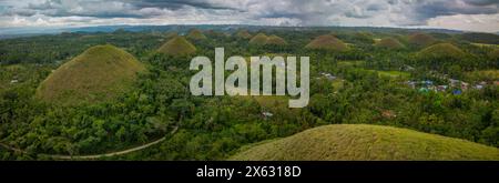 Una vista panoramica delle famose Chocolate Hills a Bohol, Filippine, che mostra le formazioni geologiche naturali a forma di cono tra una vegetazione lussureggiante Foto Stock