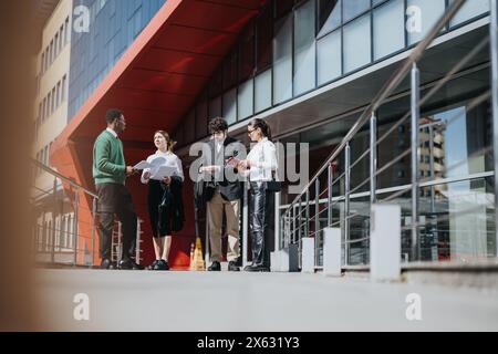 Colleghi d'affari che collaborano a un progetto in un ambiente urbano nelle giornate di sole Foto Stock
