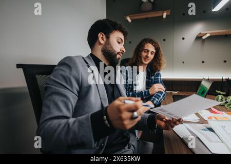 Due colleghi professionisti di sesso maschile che collaborano a un progetto in un ufficio moderno Foto Stock