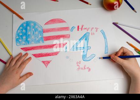 Le mani del bambino dipingono la bandiera americana su un tavolo bianco. Disegno per bambini della bandiera d'America. Giorno dell'indipendenza, 4 luglio. Foto di alta qualità Foto Stock