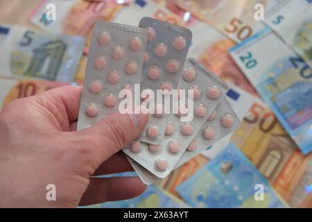 Una mano tiene la medicina davanti alle banconote in euro Foto Stock