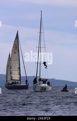 Bodrum, Turchia. 25 febbraio 2024: Giovane impiccato e ripara l'albero dello yacht High Up Stock Photo Foto Stock