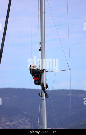 Bodrum, Turchia. 25 febbraio 2024: Giovane impiccato e ripara l'albero dello yacht High Up Stock Photo Foto Stock