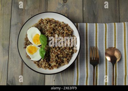 grano saraceno, uova sode, erbe aromatiche, basilico, cucchiaio, forchetta su un tovagliolo. Vista dall'alto. Il concetto di una deliziosa colazione a pranzo. Piatti slavi. Foto Stock