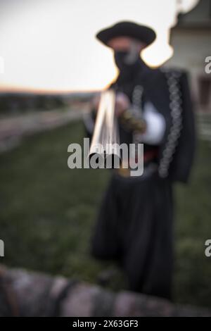 Uomo fuorilegge con fucile rivolto verso la telecamera, profondità di campo Foto Stock