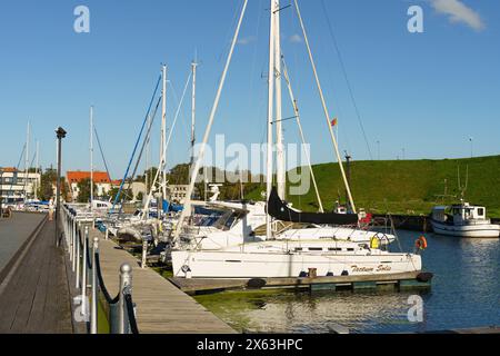 Klaipeda, Lituania - 11 agosto 2023: Un gruppo di barche a vela sono ormeggiate in sicurezza in un porto turistico, con i loro alberi alti e le vele ben volute. La calma W Foto Stock