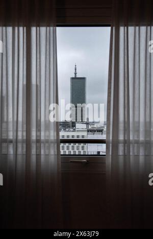 Moderno edificio in vetro visto dall'interno di una camera attraverso una finestra con tende. Si trova nella città di Varsavia, la capitale della Polonia Foto Stock