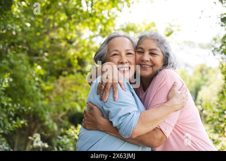 Diverse amiche anziane che si abbracciano all'aperto e sorridono alla telecamera Foto Stock