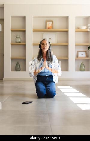 A casa, donna caucasica matura con capelli grigi che pratica yoga Foto Stock
