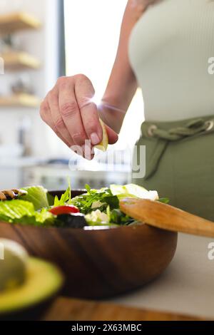 A casa, donna caucasica matura con rughe visibili che preparano l'insalata Foto Stock