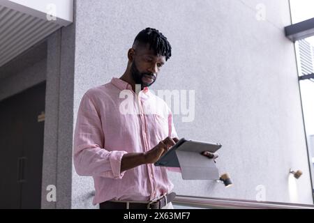 Un uomo afroamericano di mezza età legge da un tablet in ufficio Foto Stock