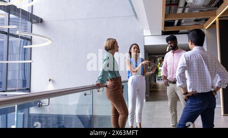 Un team diversificato di professionisti parla nel corridoio dell'ufficio, nello spazio di copia Foto Stock