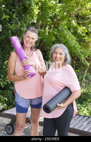 All'aperto, diverse amiche anziane con stuoie da yoga e sorridenti Foto Stock