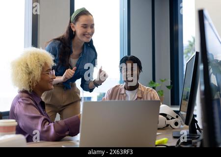 In un ufficio moderno, giovani e eterogenei che condividono idee al computer Foto Stock