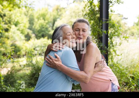 All'aperto, diverse amiche anziane si abbracciano e indossano abiti casual Foto Stock