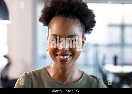 In ufficio, donna d'affari afroamericana sorridente, con abiti casual Foto Stock