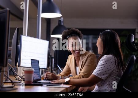 In ufficio, diverse colleghe d'affari discutono di lavoro e lavorano fino a tardi Foto Stock