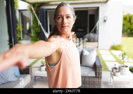 A casa, donna caucasica matura che fa yoga nel suo cortile Foto Stock