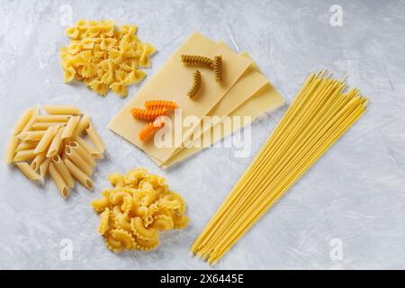 Varietà di tipi e forme di pasta italiana su sfondo grigio, vista dall'alto Foto Stock