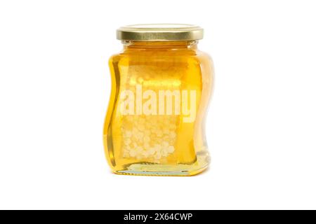 Un vaso di vetro con coperchio dorato contiene miele con favo riempito quasi fino in cima, su sfondo bianco Foto Stock