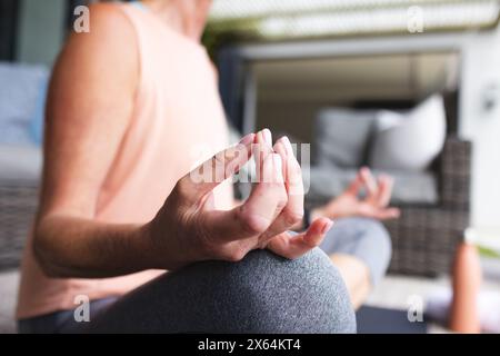 A casa, donna caucasica matura che pratica yoga, concentrandosi sulla posizione della mano Foto Stock