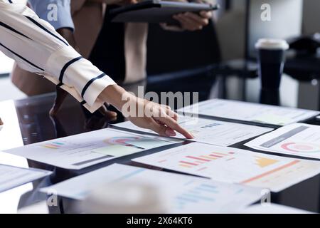 Un team diversificato in ufficio, inclusa una donna caucasica di mezza età, che esamina i documenti Foto Stock