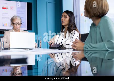 Donne caucasiche e birazziali in un abbigliamento elegante discutono in un ufficio Foto Stock