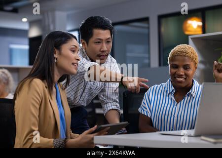Scena dell'ufficio con team diversi: Uomo asiatico, donna afroamericana, schermo di visualizzazione Foto Stock