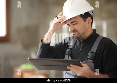 Deluso il lavoratore edile che ha controllato il tablet in una casa Foto Stock