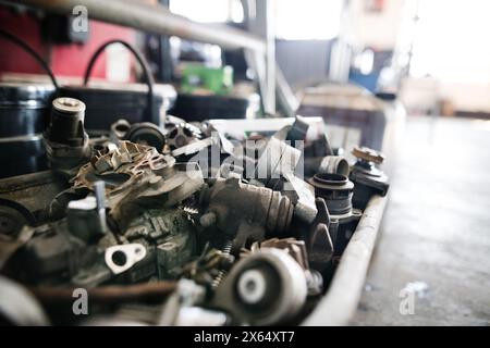 Componenti in metallo, parti su banco di lavoro in officina di riparazione auto. Meccanici che riparano, mantengono l'auto in un garage, Foto Stock