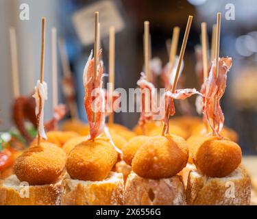 Pinchos baschi (una forma di tapas spagnole), con pane e prosciutto spagnolo, in un bar. Spuntino tipico dei Paesi Baschi, pinchos o spiedini di pinxtos Foto Stock
