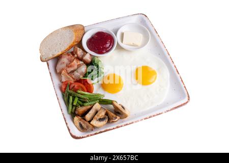 Piatto della colazione, uova fritte, pancetta, funghi arrostiti, verdure e condimenti su sfondo bianco isolato Foto Stock