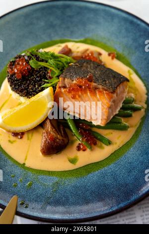 Filetto di salmone con salsa cremosa, quinoa e verdure su un piatto, pasto gustoso Foto Stock